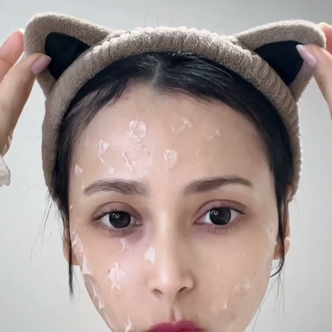 머리에 고양이 귀 모양 헤어밴드를 쓴 크리에이터가 집에서 얼굴에 필오프 팩을 올린 채 카메라를 보는 장면. 화면 위에 영어 자막이 있다