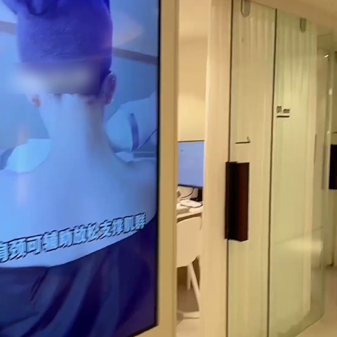 클리닉 복도 스크린에서 중국어 자막이 들어간 영상이 재생되는 장면