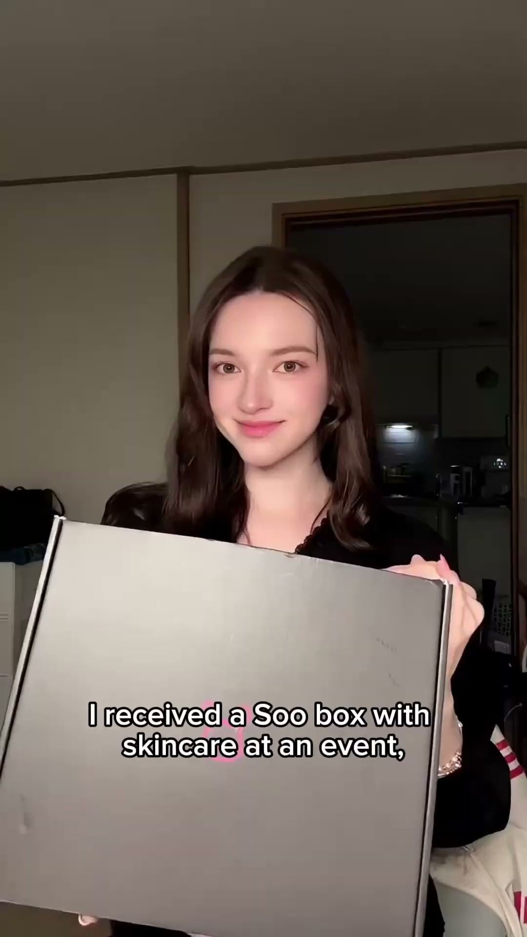 집 안에서 수하우스 선물 박스를 들고 카메라를 보는 크리에이터. 화면에 행사에서 스킨케어 박스를 받았다는 영어 자막이 떠 있다