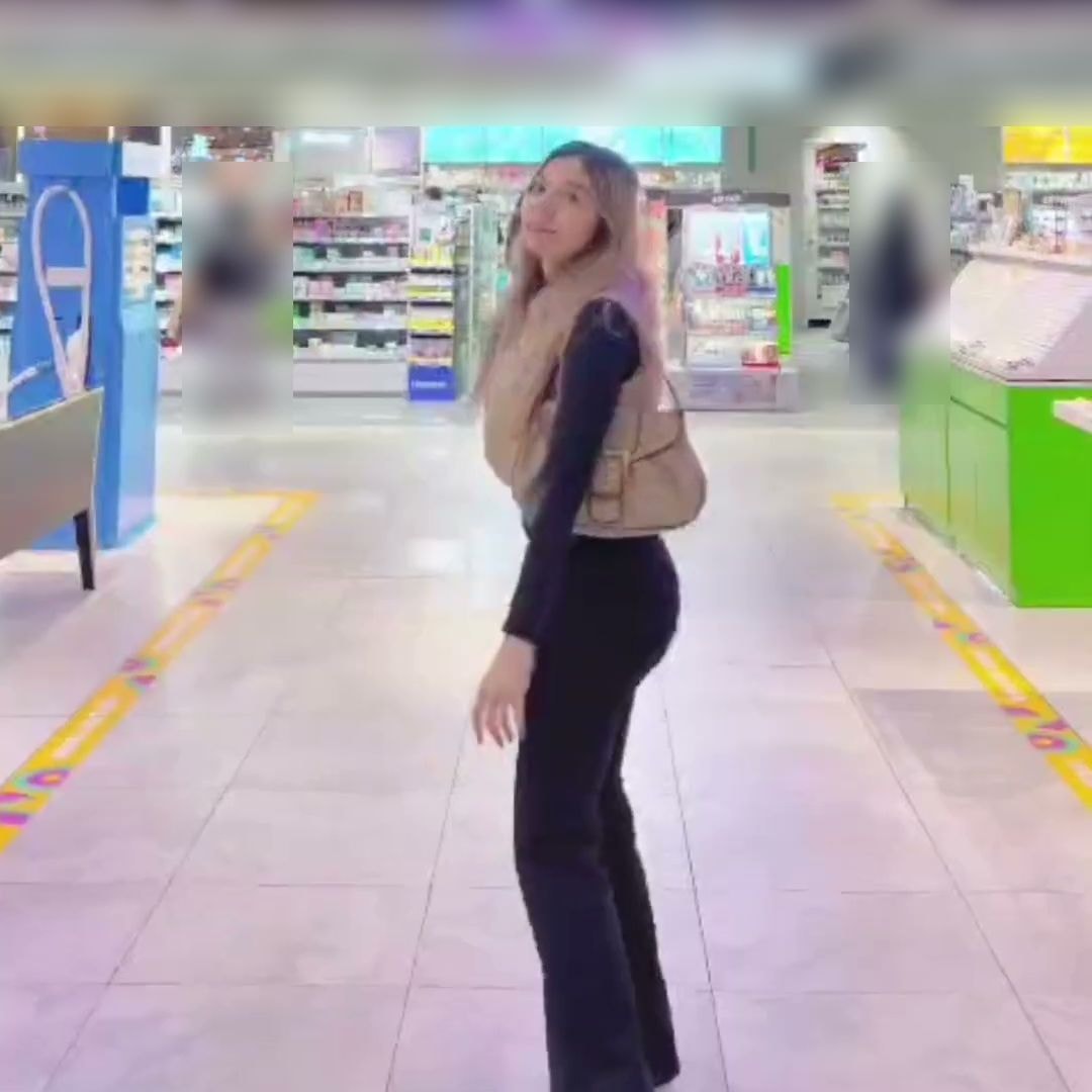 매장 통로 한가운데서 뒤돌아 카메라를 보는 크리에이터. 뒤편 매장 간판과 지나가는 방문객은 흐리게 처리했다