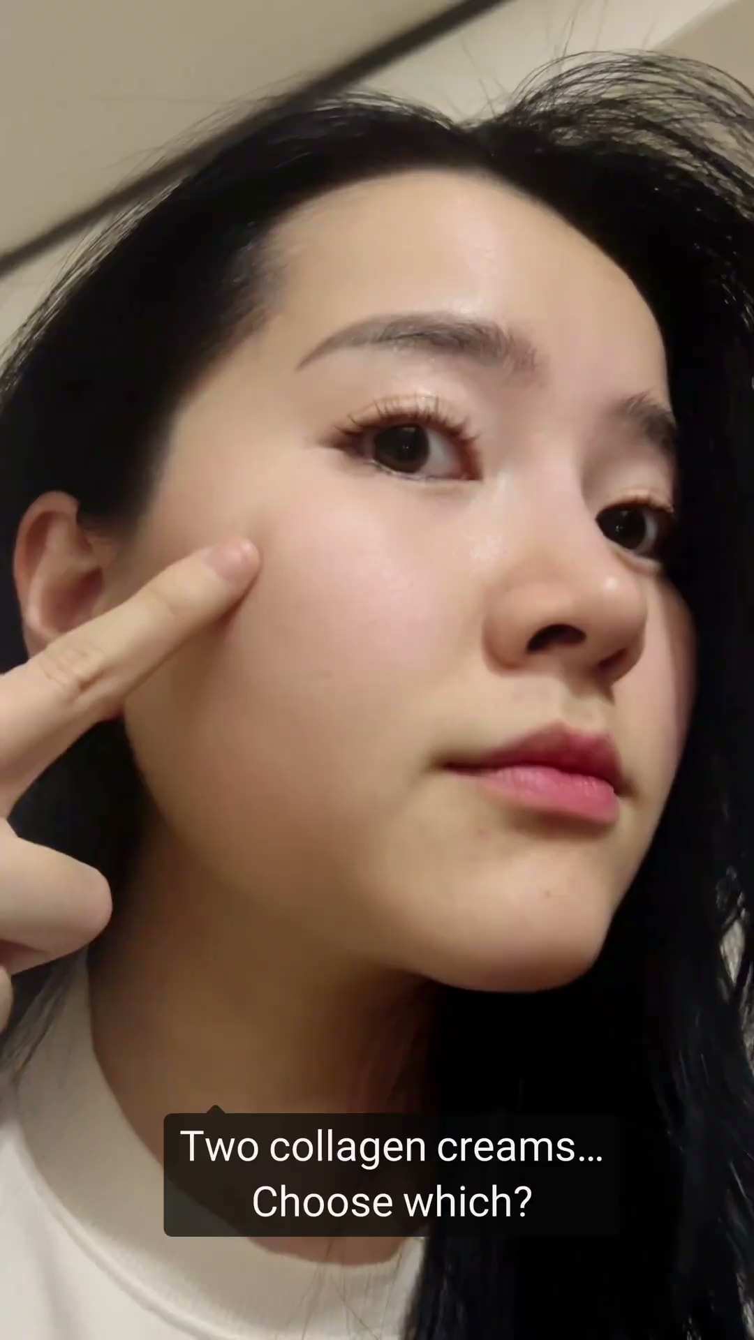 'Two collagen creams… Choose which?' 영어 자막이 아래쪽에 얹힌 세로형 숏폼 컷 — 베트남 출신 크리에이터가 손끝으로 볼을 가리키고 있습니다