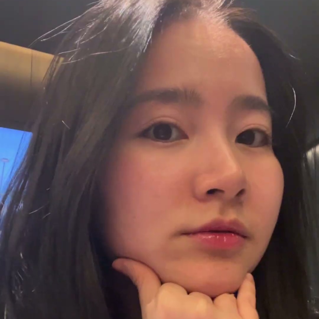 실내에서 턱을 괴고 카메라를 응시하는 베트남 출신 크리에이터의 클로즈업 컷