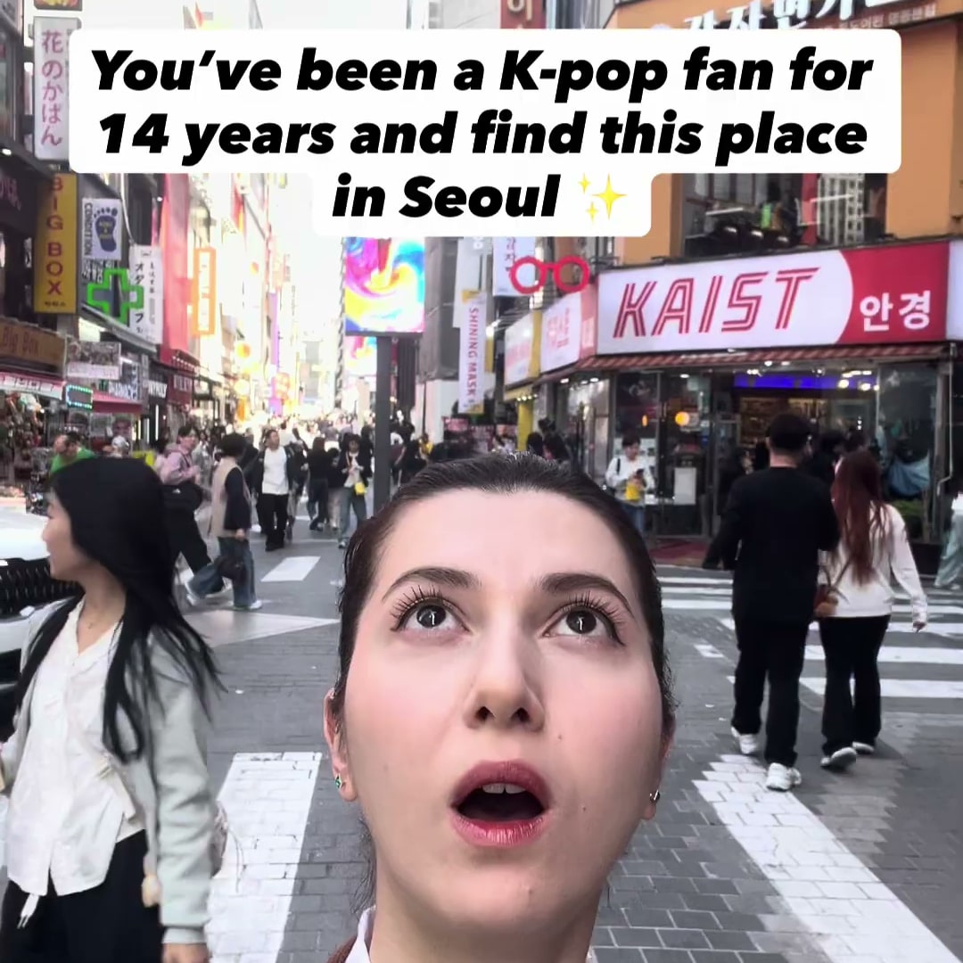 번화가 거리에서 위를 올려다보는 크리에이터와 영어 자막이 함께 담긴 콘텐츠 장면