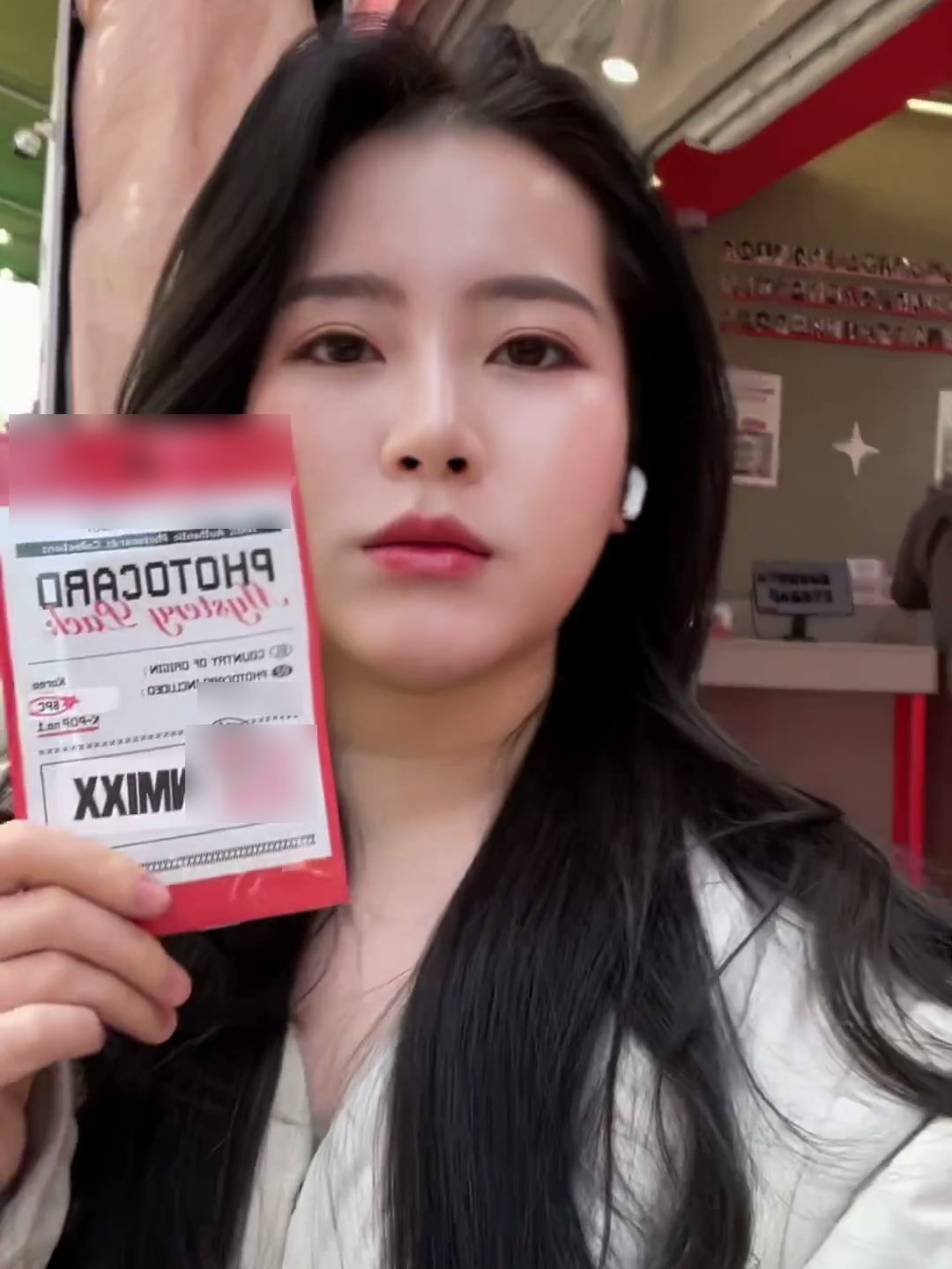 매장 안에서 크리에이터가 구매한 상품 봉투를 카메라 앞으로 들어 보이는 장면. 브랜드 표기는 흐림 처리했다