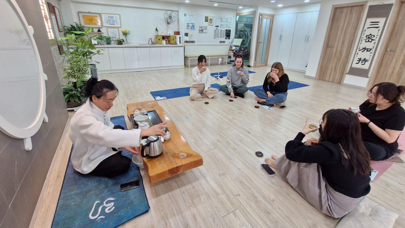 한옥풍 실내 공간에서 외국인 참가자들이 둘러앉아 한국 전통 다도 체험 클래스에 참여하고 있다.
