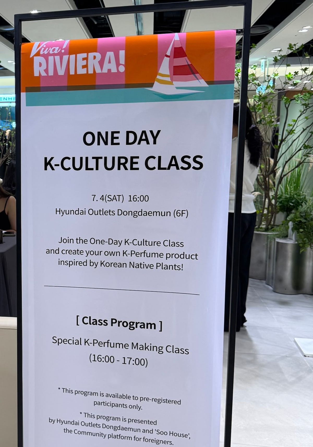 백화점 실내에 세워진 세로 안내 배너. ONE DAY K-CULTURE CLASS, 7. 4(SAT) 16:00, Hyundai Outlets Dongdaemun (6F), Special K-Perfume Making Class (16:00 - 17:00), pre-registered participants only 라고 적혀 있고 아래에 Soo House 가 함께 진행한다는 안내가 있다.